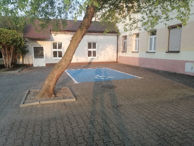 Zdjęcie: miejsce postojowe dla osoby niepełnosprawnej. Miejsce oznaczone kolorystycznie. Posiada odpowiednie wymiary.